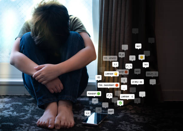 Social media cyberbullying shown by a sad teenager surrounded by abusive messages on a smartphone.